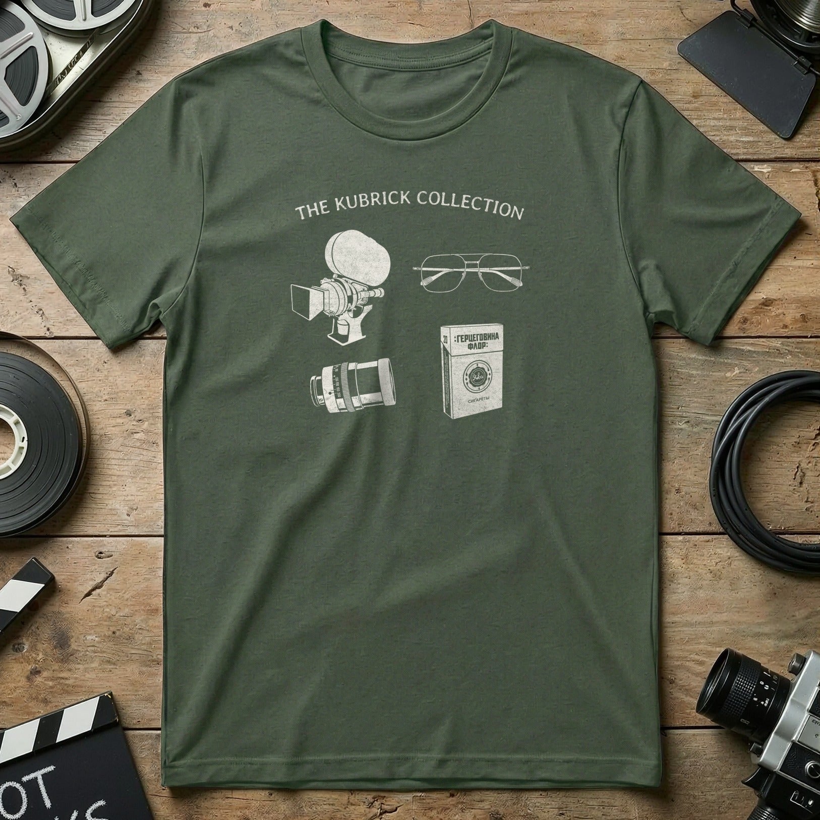 Green t-shirt with line drawings of a film camera, glasses, and a book titled "The Kubrick Collection."