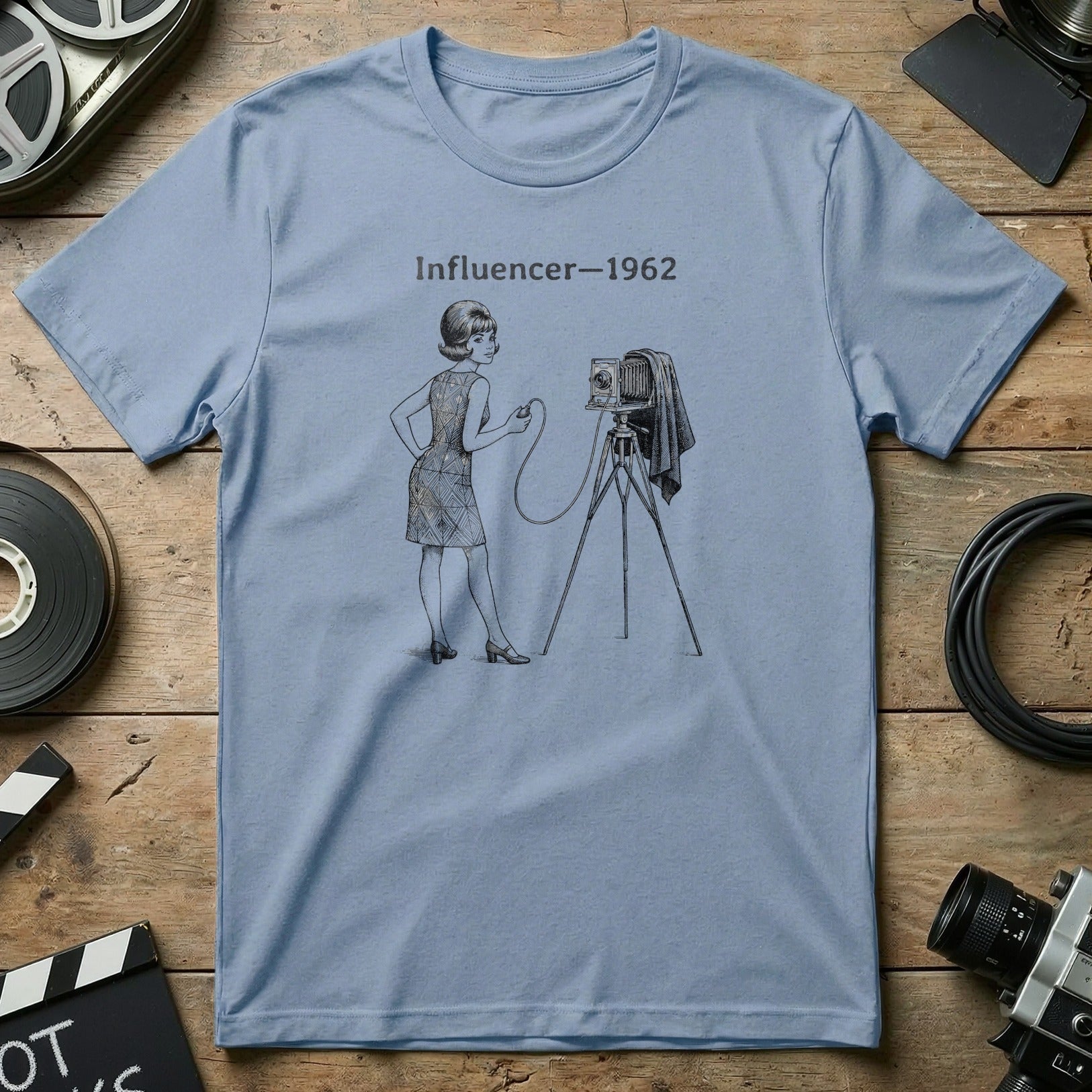 Light blue t-shirt with illustration of a woman and vintage camera, text "Influencer 1962".