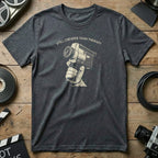 Dark gray t-shirt with "Still Cheaper Than Therapy" and vintage camera graphic.
