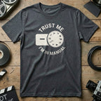 Dark gray t-shirt with "Trust Me I'm IN MANUAL" and camera mode dial graphic.