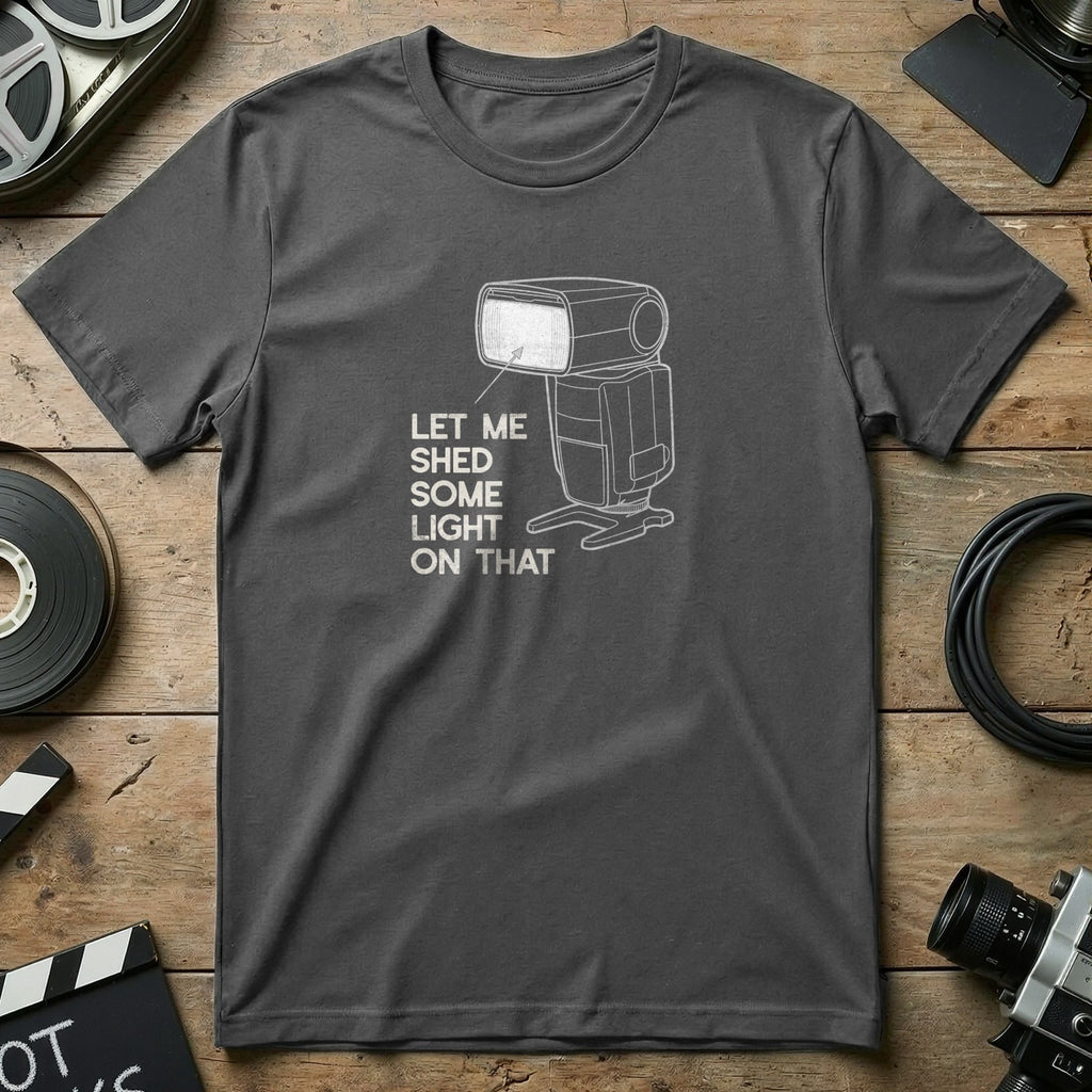 Dark grey t-shirt with a graphic of a camera flash and text that reads "Let me shed some light on that."