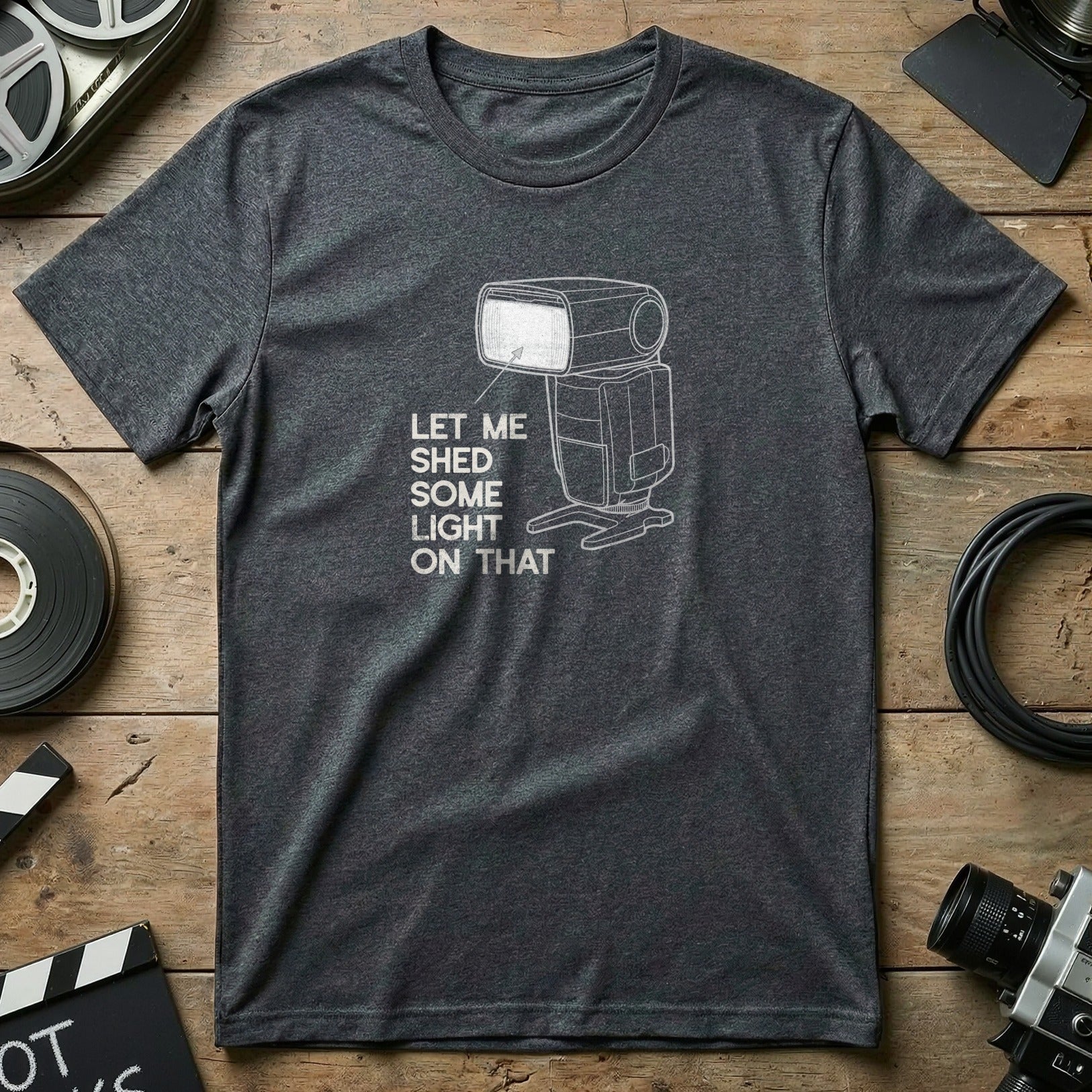 Dark grey t-shirt with text "Let me shed some light on that" and a graphic of a camera flash.