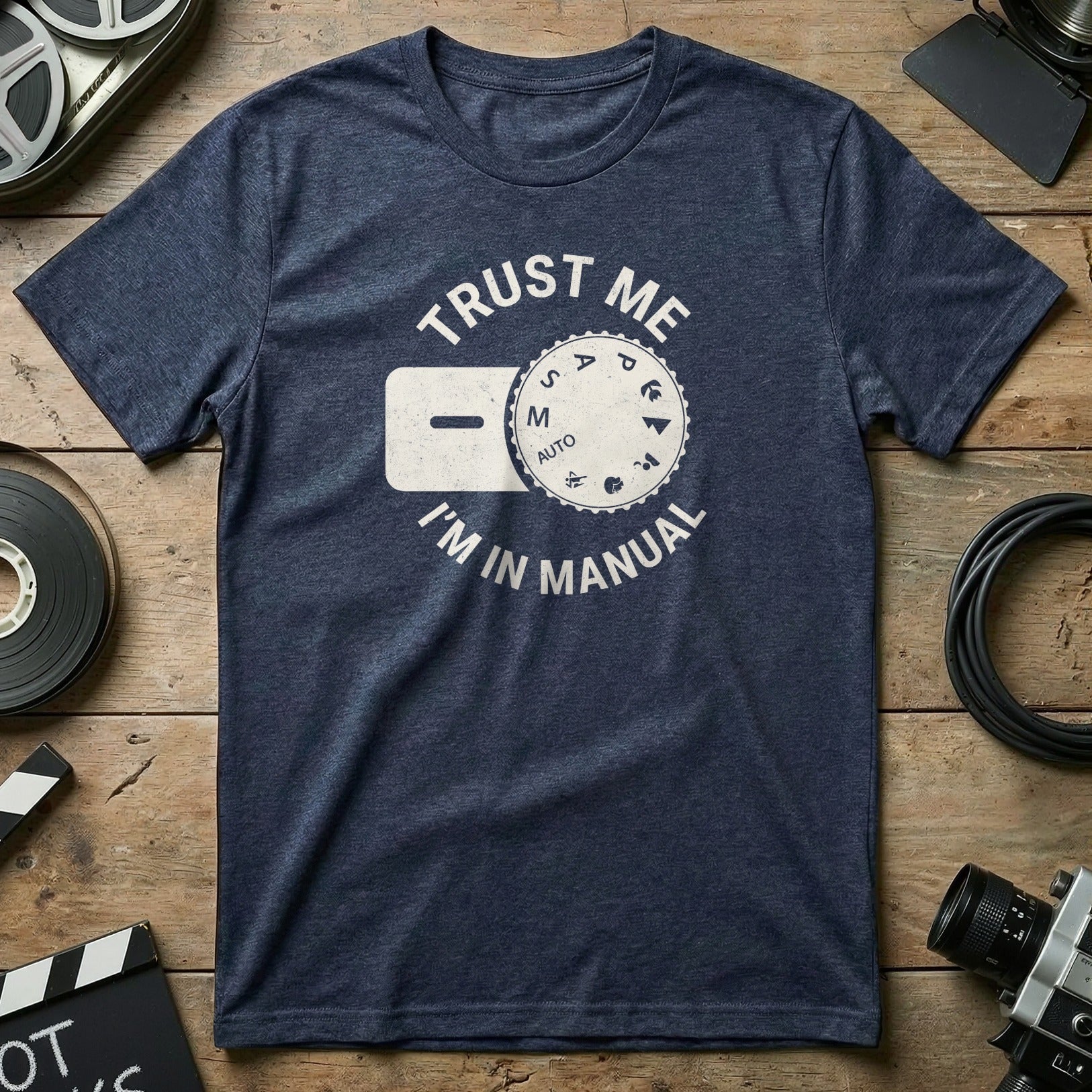 Navy t-shirt with "TRUST ME I'M IN MANUAL" and a camera dial graphic.